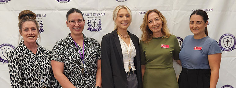 Five staff member smiling at an assembly