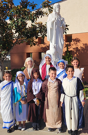 Students in costume in front of a statue